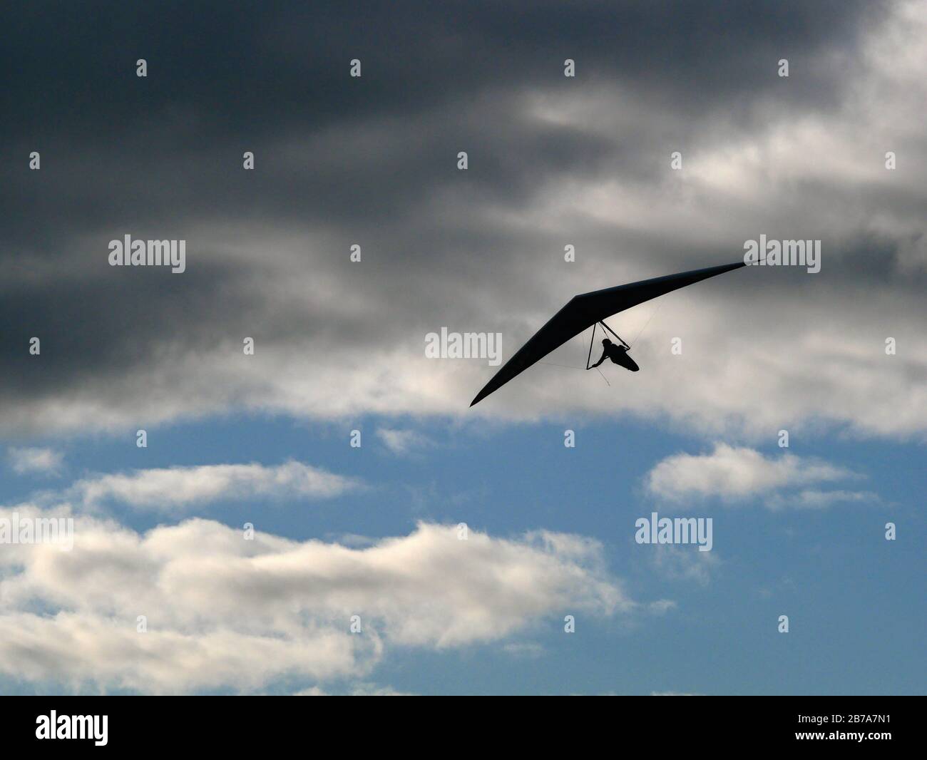 Hang glider silhouetted against clouds Stock Photo