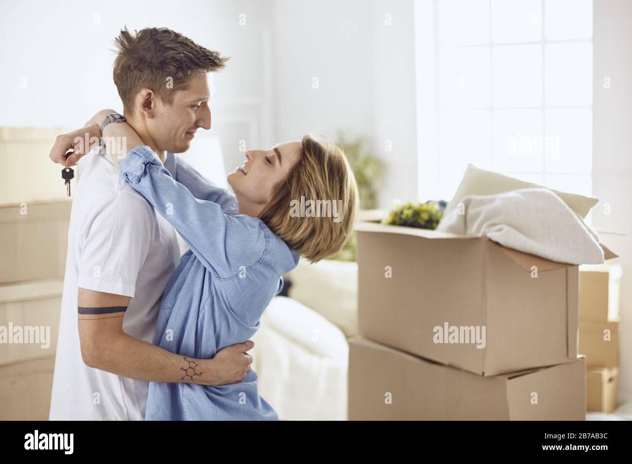 Happy smiling young couple showing a pair of keys of their new house ...