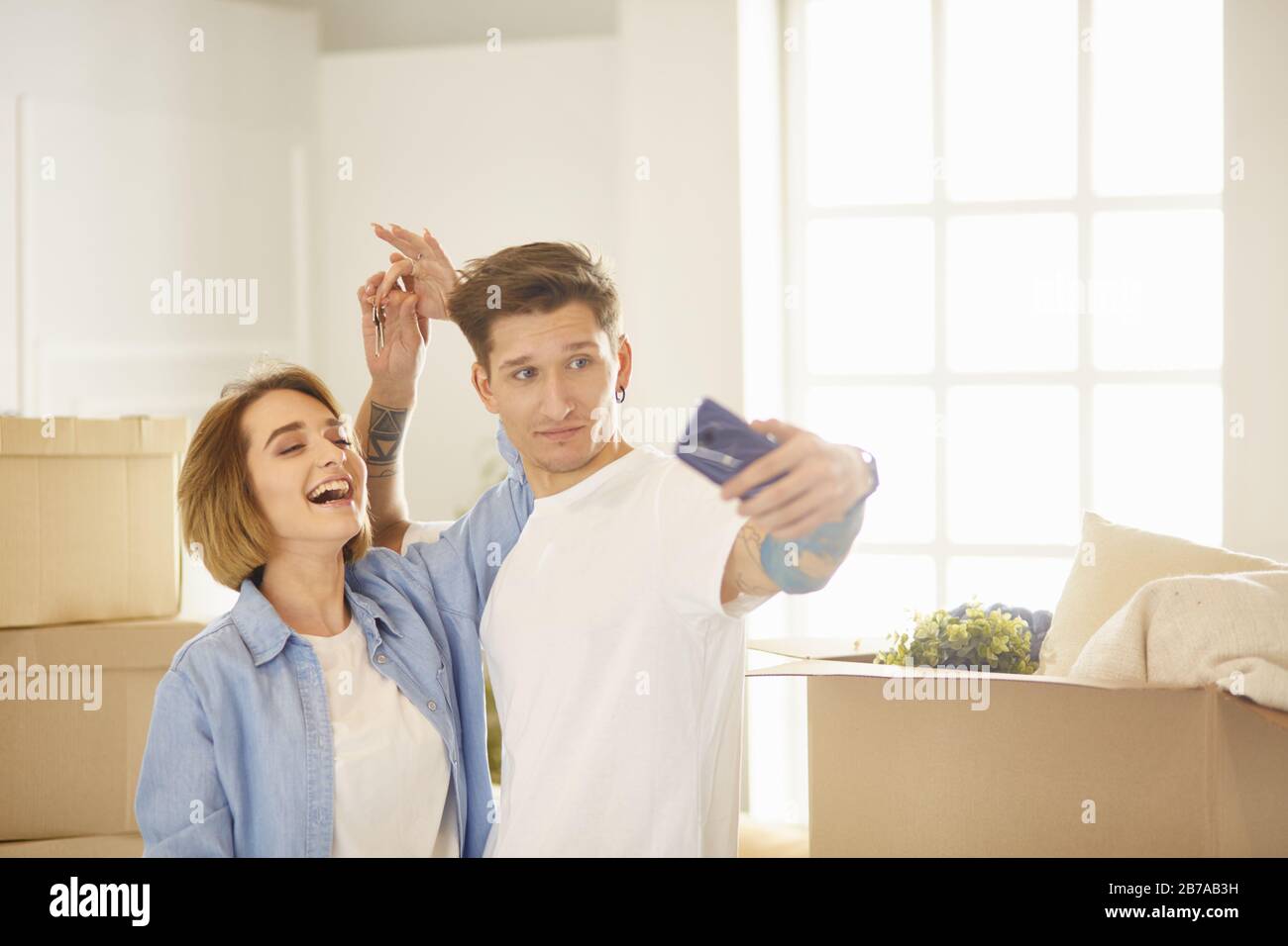 Happy smiling young couple showing a pair of keys of their new house ...