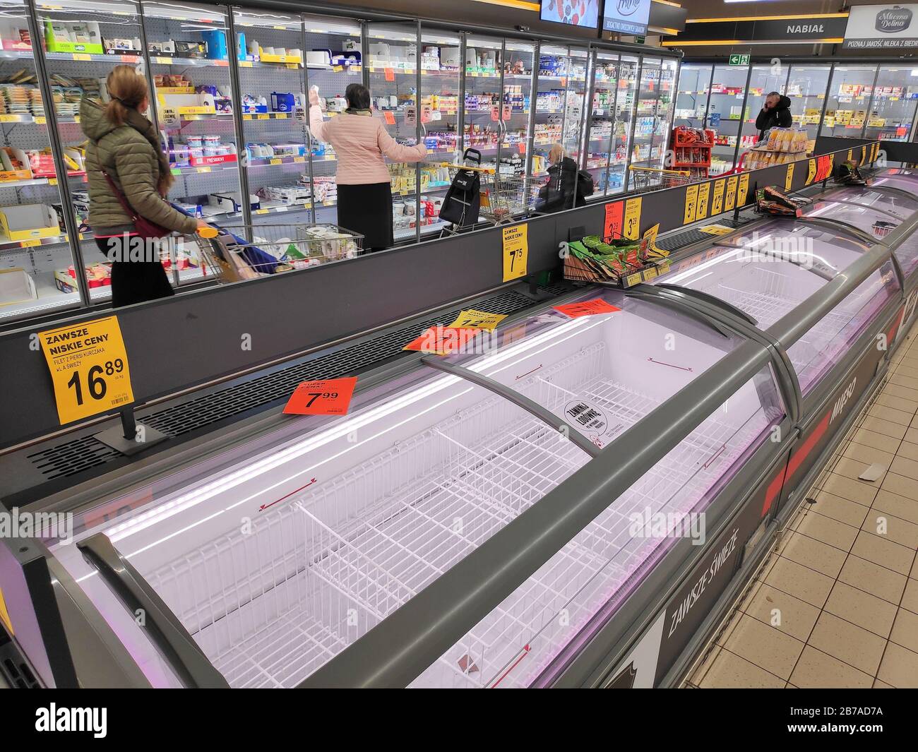 KATOWICE, POLAND - MARCH 14, 2020: People walk by empty meat refrigerators in a supermarket in Poland. Local people stockpiled food in anticipation of Stock Photo