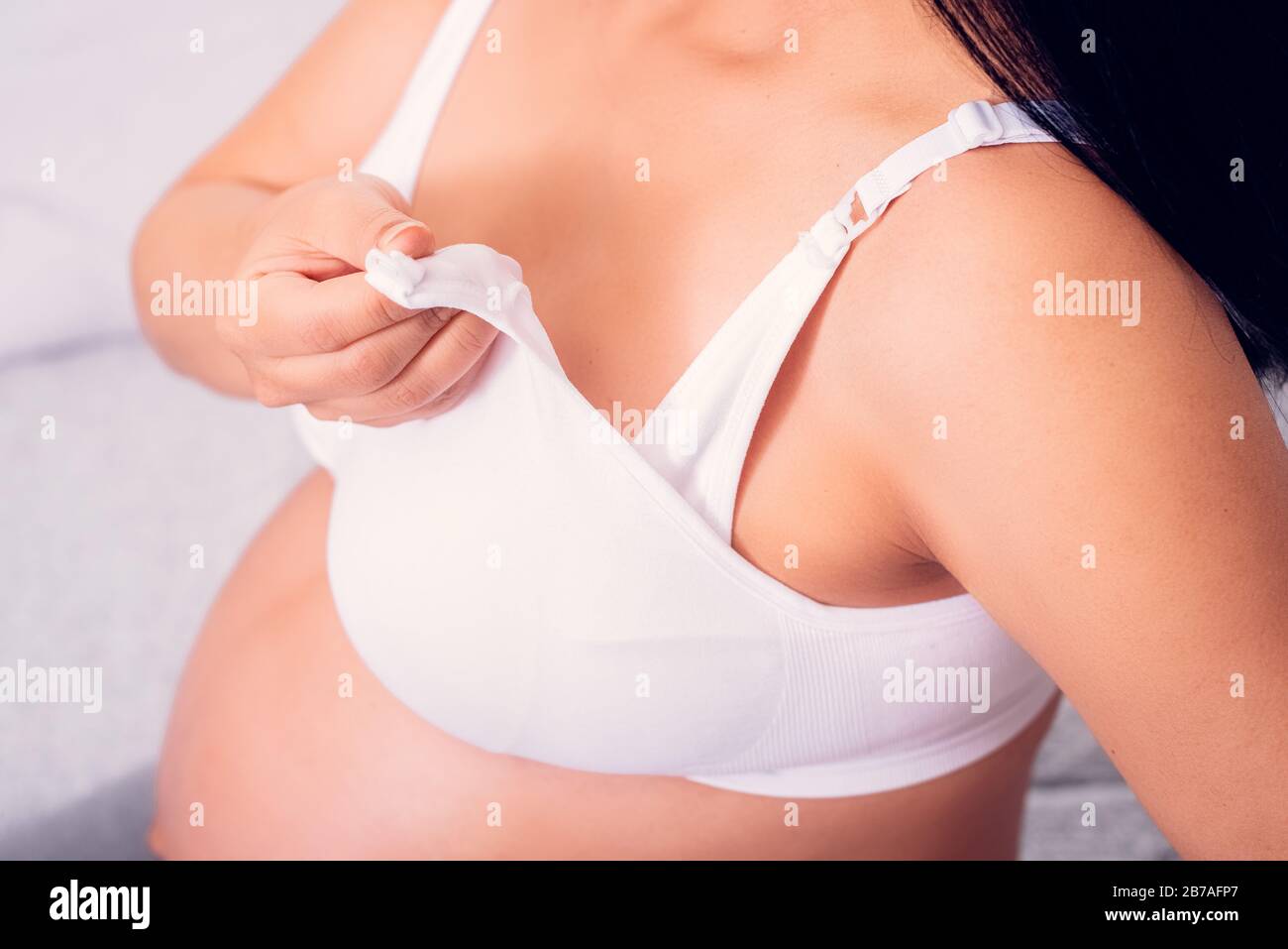 Pregnant woman holding nursing bra with easy breast access for baby feeding. Stock Photo
