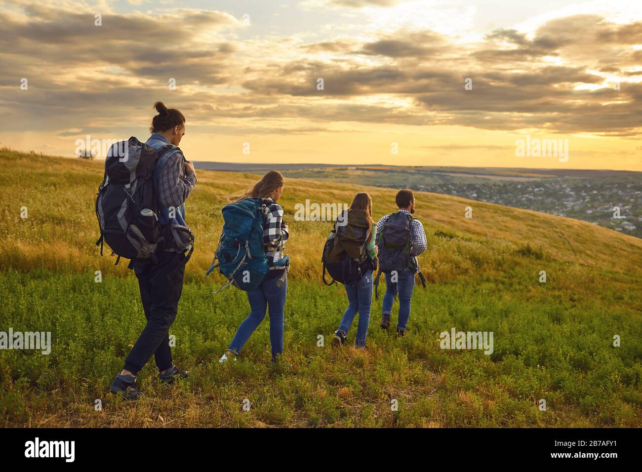 Group of people trekking with backpacks walking on the hill . Stock Photo