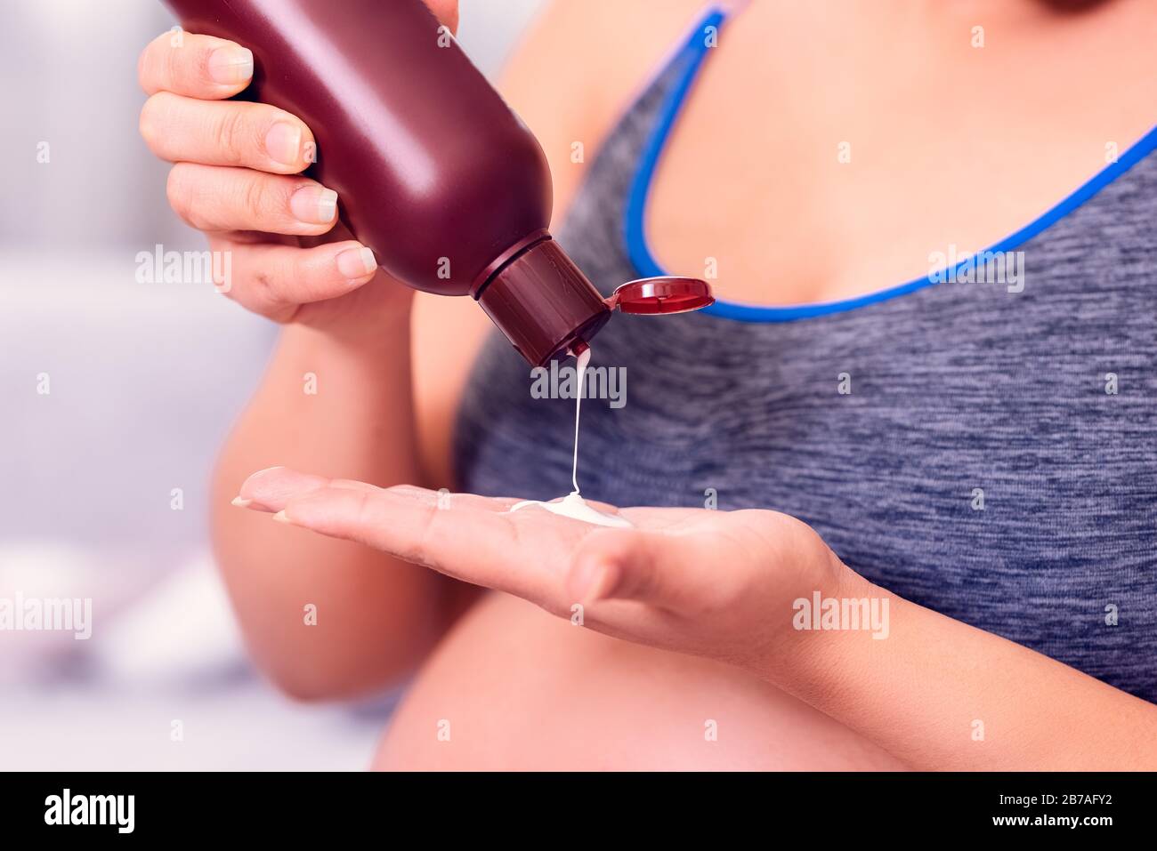 Pregnant woman applying body lotion on the hand. Stock Photo
