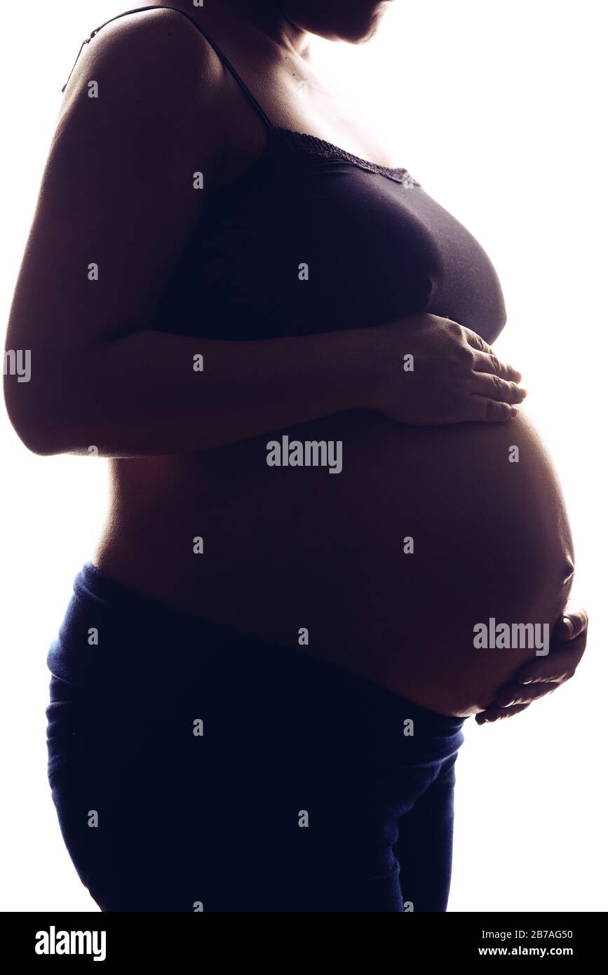 Silhouette portrait on the white background of a pregnant woman, holding belly with two hands. Stock Photo