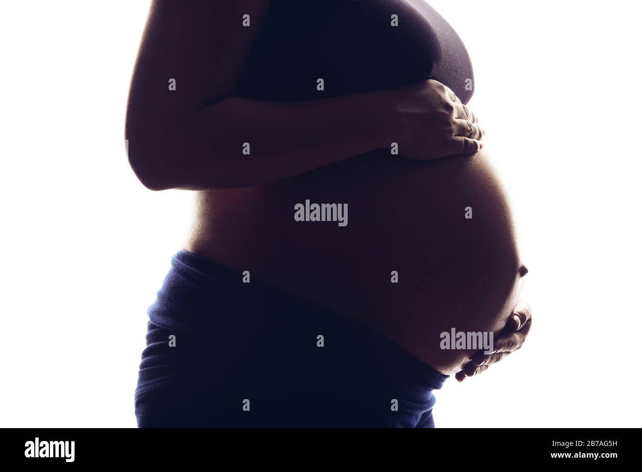 Silhouette portrait on the white background of a pregnant woman, holding belly with two hands. Stock Photo