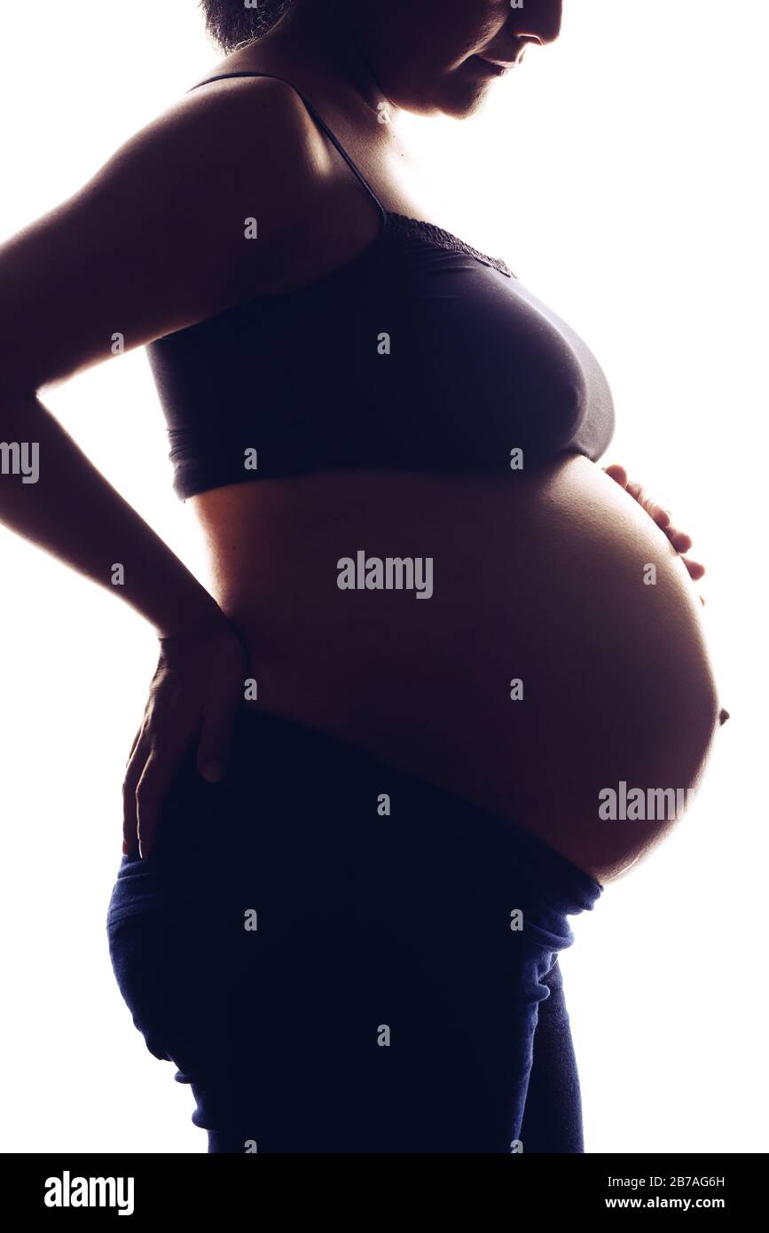Silhouette portrait on the white background of a pregnant woman, holding belly with two hands. Stock Photo
