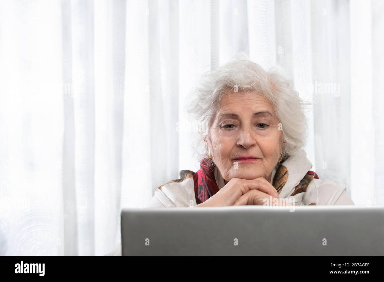 old lady looking at a computer on a wooden table. concept of technology