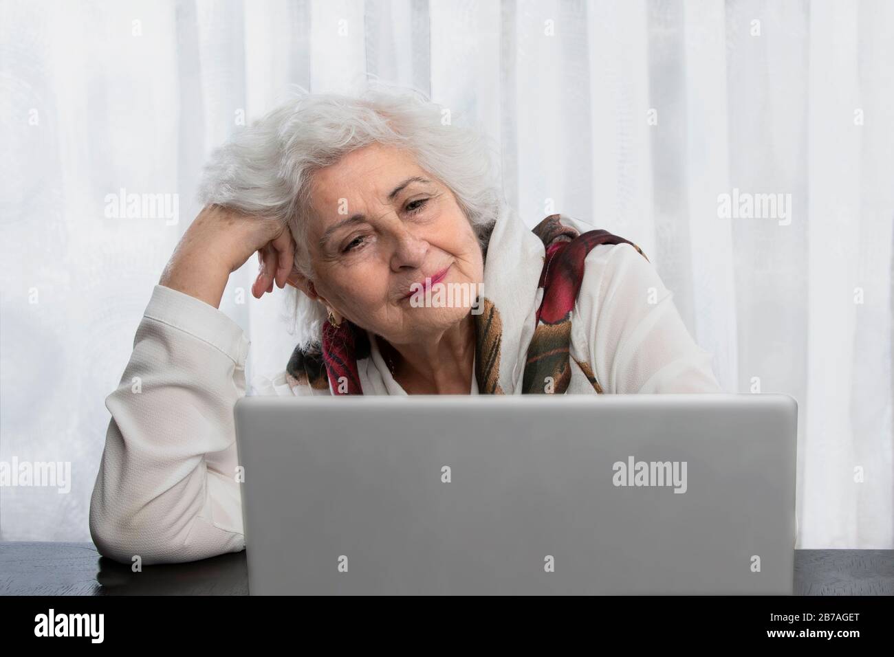 old lady looking at a computer on a wooden table. technology concept