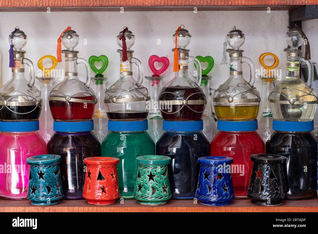 Tasseled silver topped glass bottles of colourful/colorful perfume oil and oil burners on a shelf in Essaouira, Morocco Stock Photo