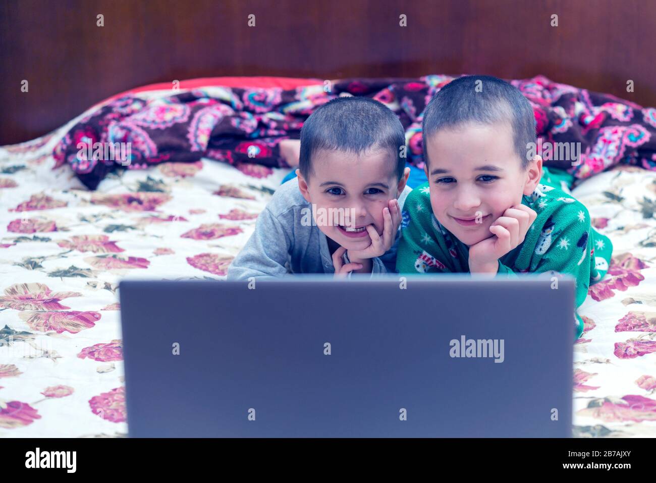wo little brothers in pajamas are watching a cartoon on a laptop. Funny children enjoying cartoons on notebook, laptop or computer. No faces of people Stock Photo