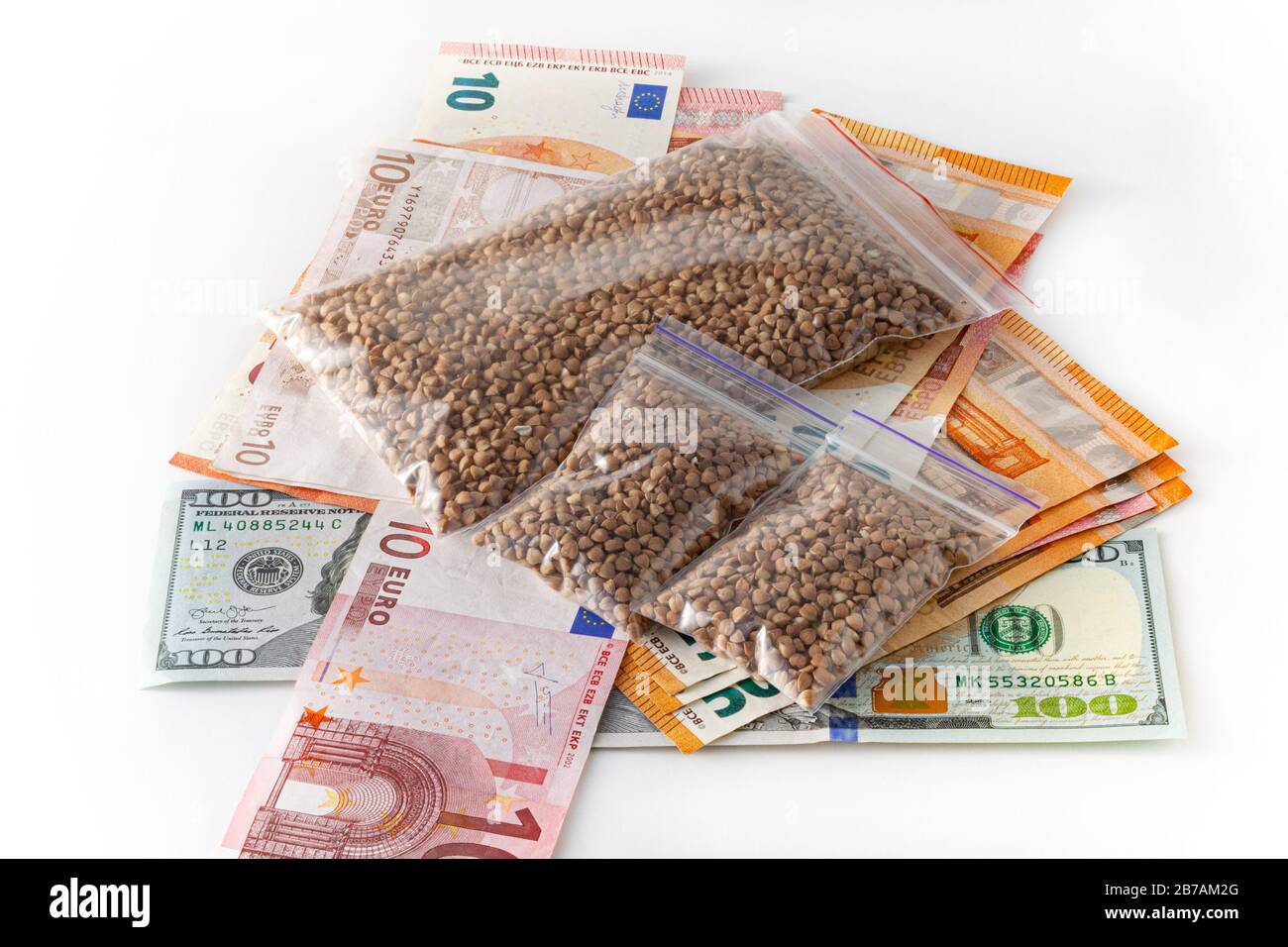 Raw buckwheat groats in small transparent plastic bags, small dose, expensive, a lot of euro money. on white background. Crisis concept Stock Photo