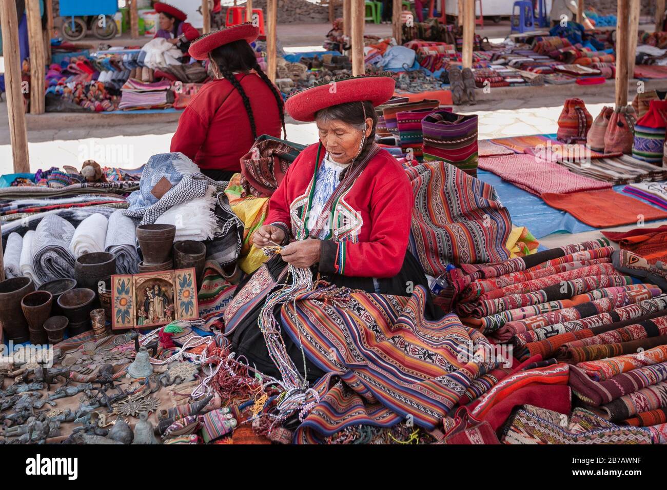 Cuzco, Peru: Quechua women in traditional indigenous clothing at market selling colorful textile making local craft souvenirs Stock Photo