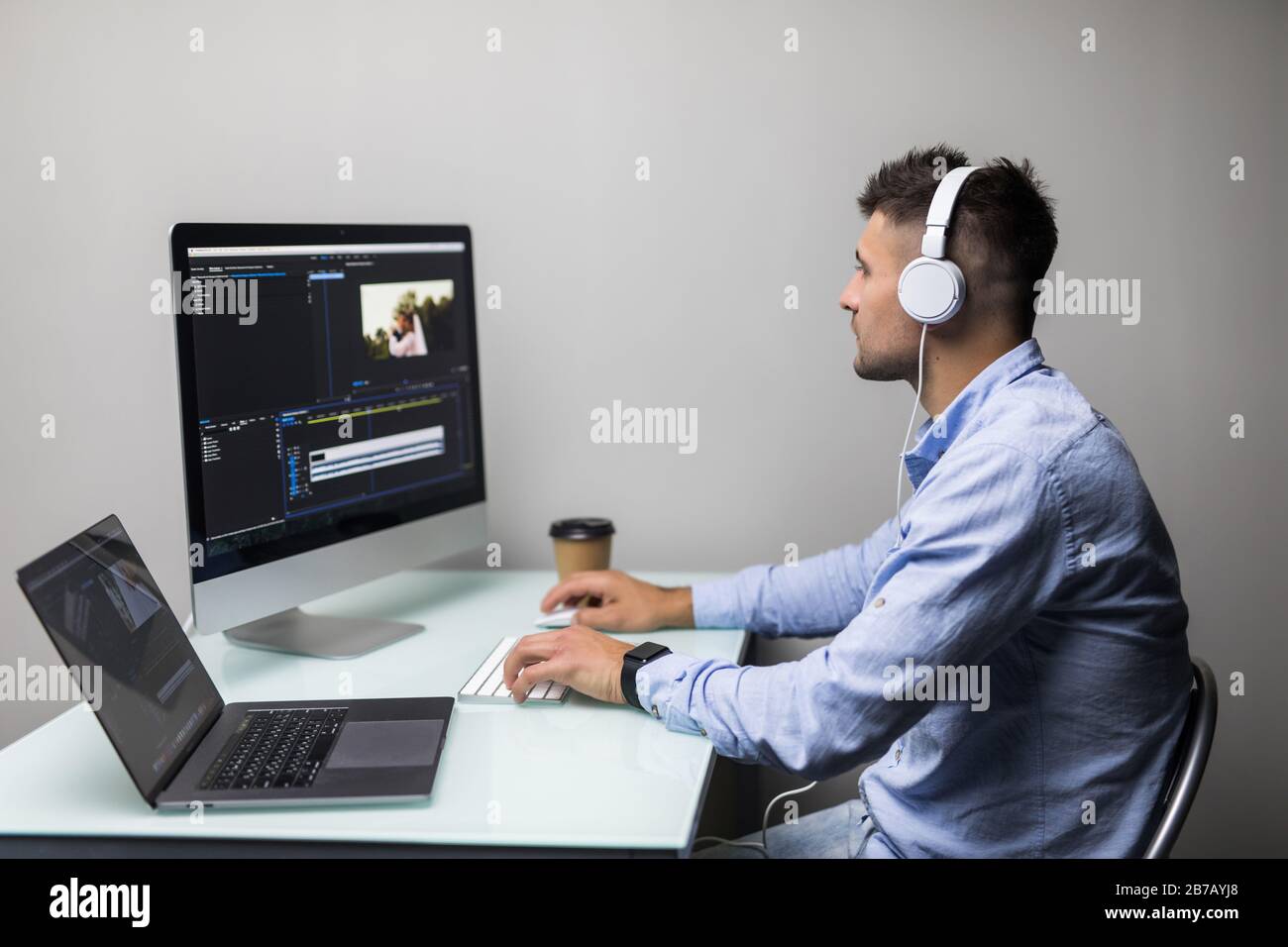 Male videographer edits and cuts footage and sound on his personal computer at his office Stock Photo