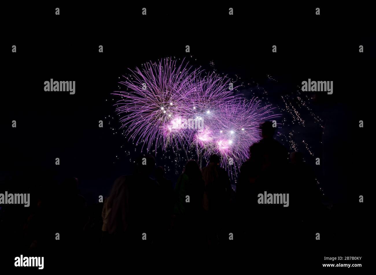 Image of a people in front of a fireworks as silhouettes. Stock Photo