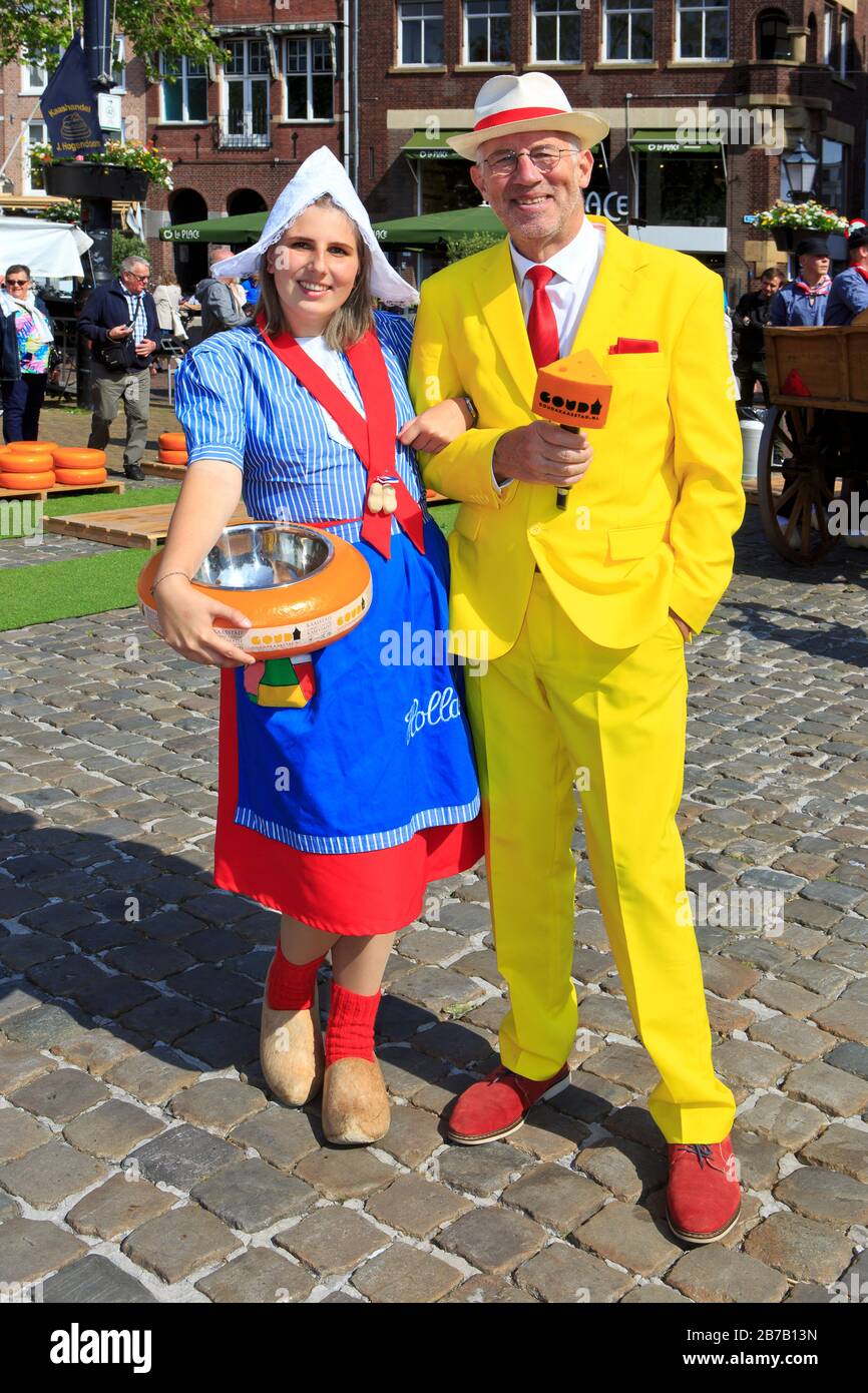 Girl in traditional Dutch attire holding a Gouda cheese ball and a host at the Cheese Market in Gouda (South Holland), Netherlands Stock Photo