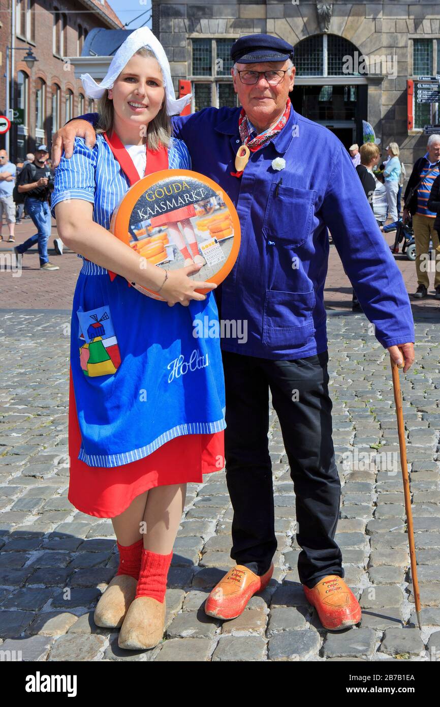 Girl in traditional Dutch attire holding a Gouda cheese ball and a cheese farmer at the Cheese Market in Gouda (South Holland), Netherlands Stock Photo