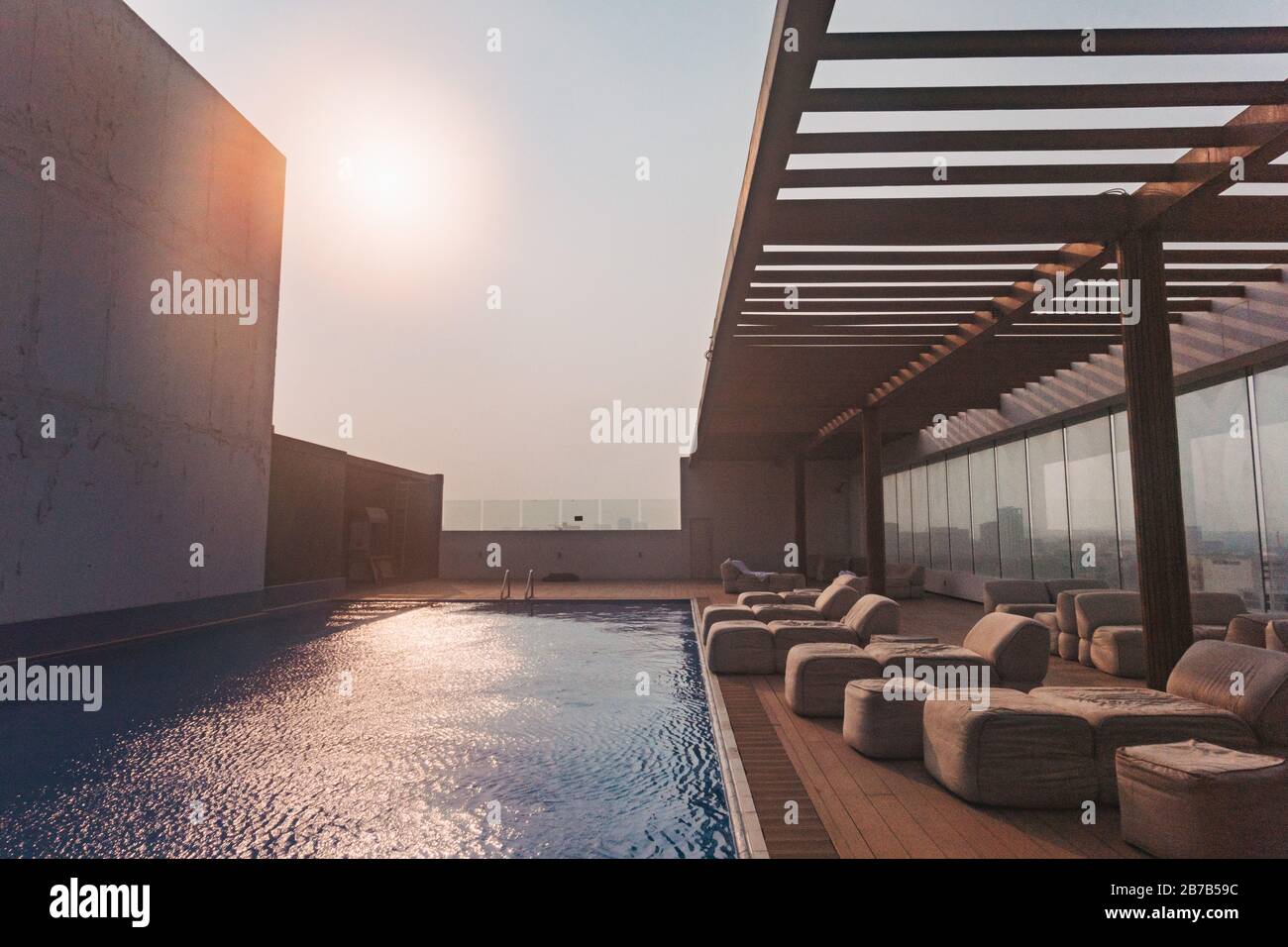 A hotel rooftop swimming pool and deckchairs on a hot afternoon in Doha, Qatar Stock Photo