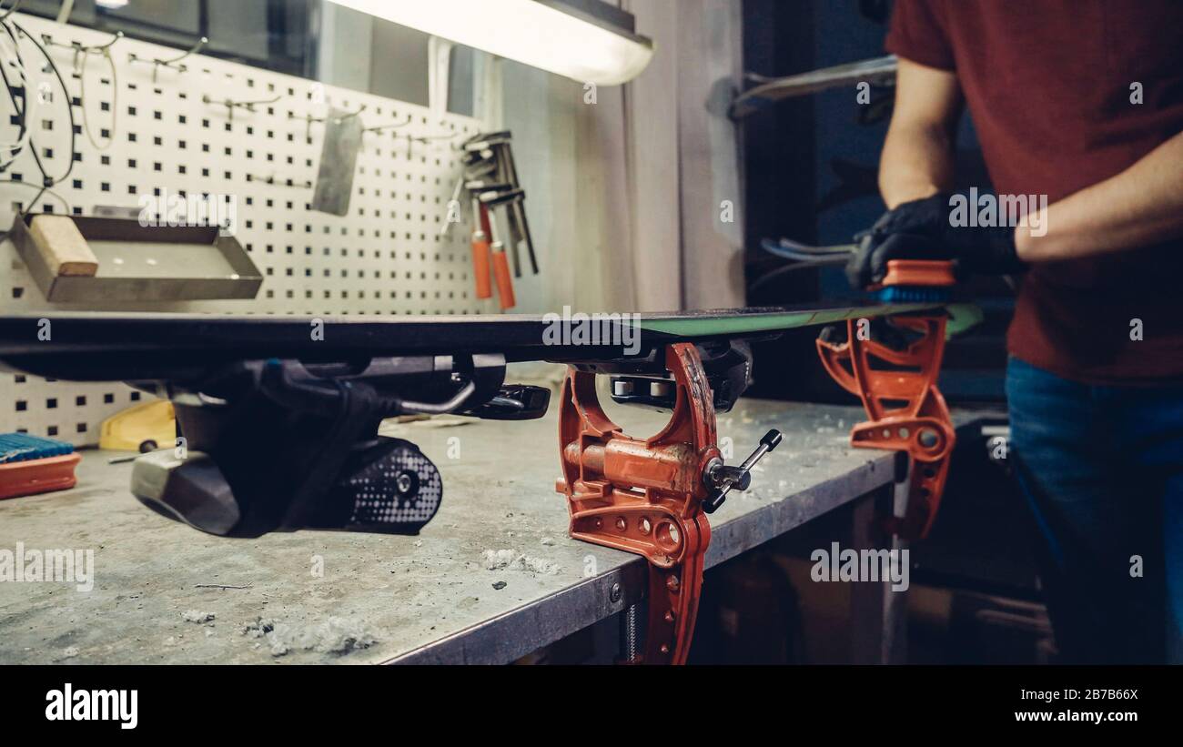 Cleaning ski base with fine hair brush. Attractive worker cleaning ski