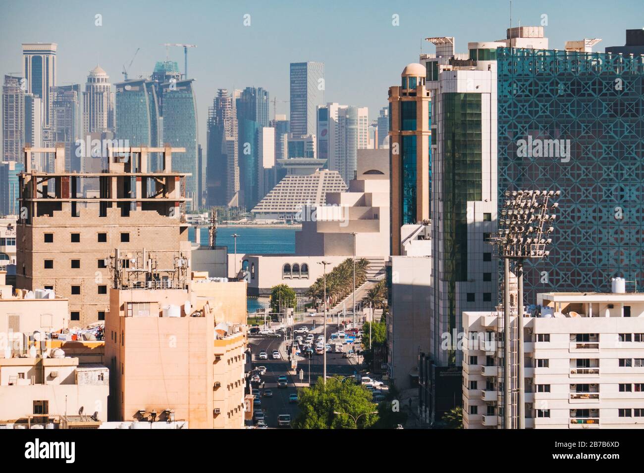 Looking between buildings down a street in Doha's Al Souq area. The iconic skyline, Sheraton and Museum of Islamic Art are visible behind Stock Photo