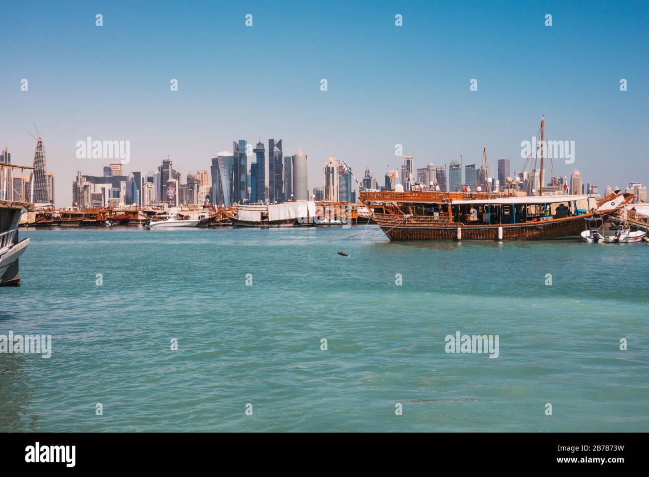 Dhow boats parked at Dhow Harbour with the financwial centre skyline visible behind, one summer morning in Doha, Qatar Stock Photo