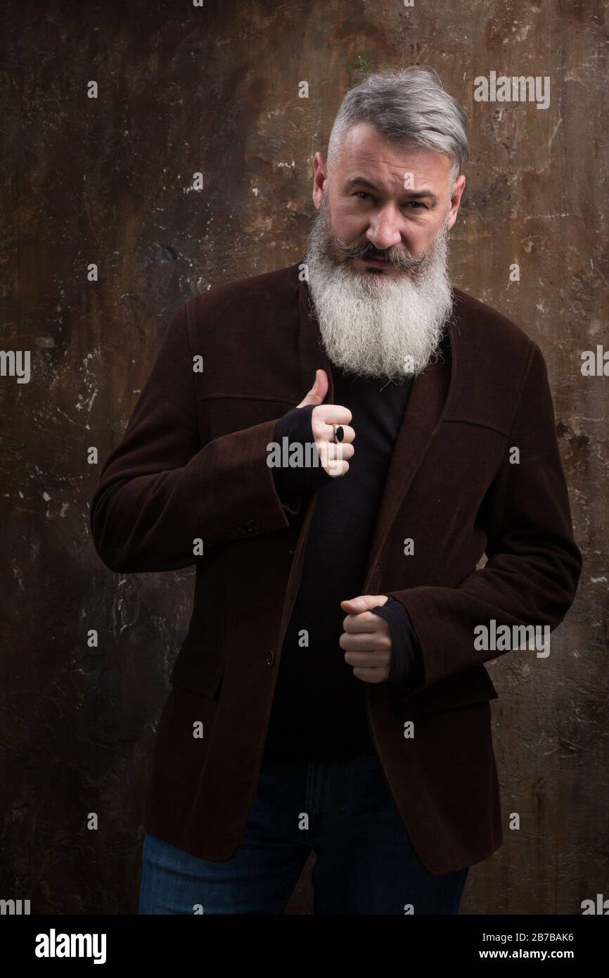 Portrait of a Middle Age Man with Beard and Mustache Posing in Informal Wear on a Dark Backdrop, selective focus Stock Photo