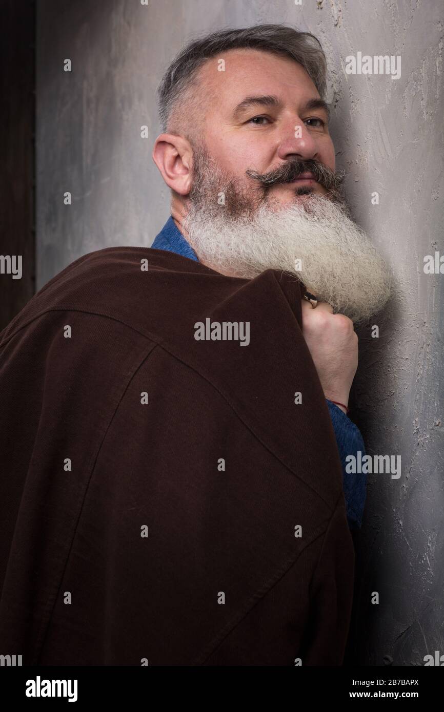 Portrait of a Middle Age Man with Beard and Mustache Posing in Informal Wear on a Dark Backdrop, selective focus Stock Photo