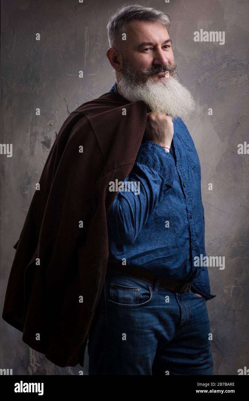 Portrait of a Middle Age Man with Beard and Mustache Posing in Informal Wear on a Dark Backdrop, selective focus Stock Photo