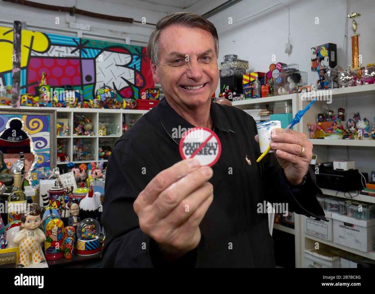 Brazilian President Jair Bolsonaro smiles as he holds up a humorous button during a visit to the art studio of Romero Britto March 8, 2020 in Miami, Florida. Stock Photo
