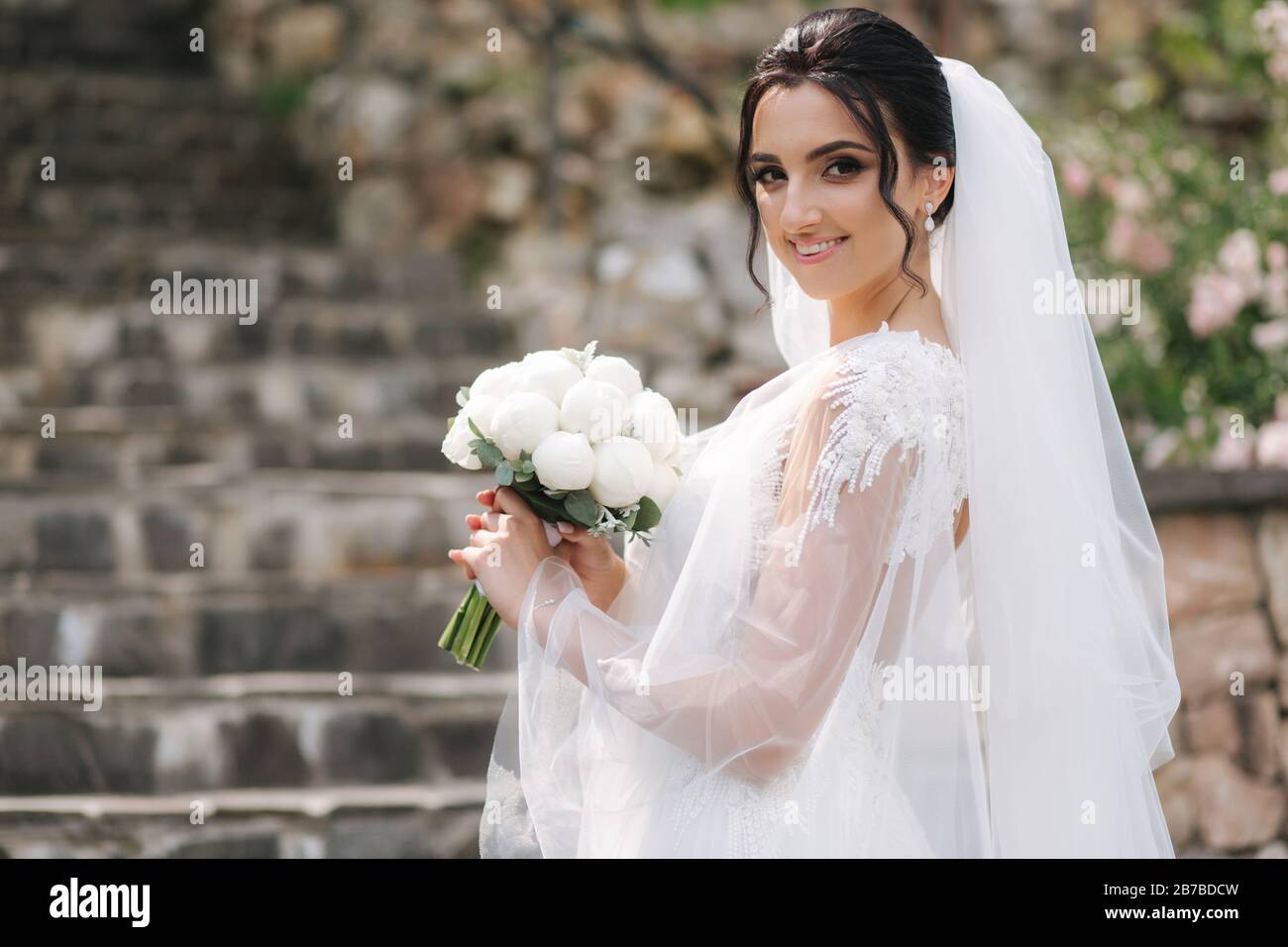 Gorgeous bride in elegant wedding dress with bouquet of white flowers ...