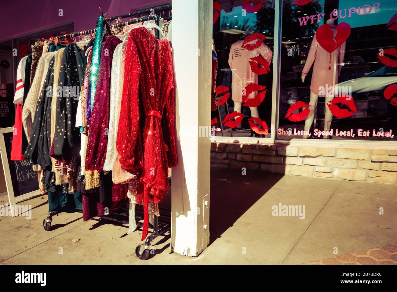 A storefront with sparkly dresses on rack outside on sidewalk of the