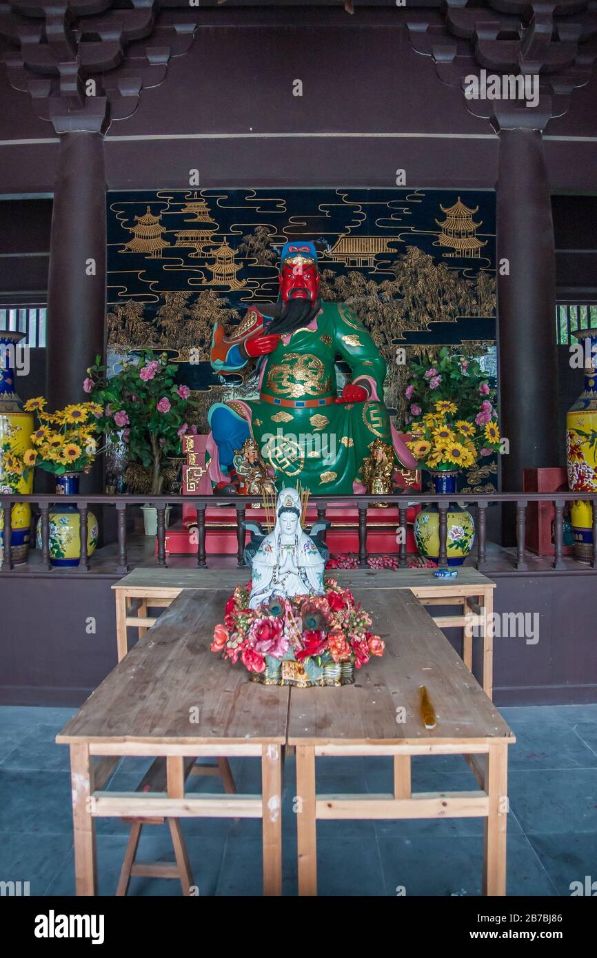 Guilin, China - May 11, 2010: Qixia Buddhist Temple in Seven Star Park. Statues of Red-faced, green-golden garb, Guan Yu God of War surrounded by flow Stock Photo