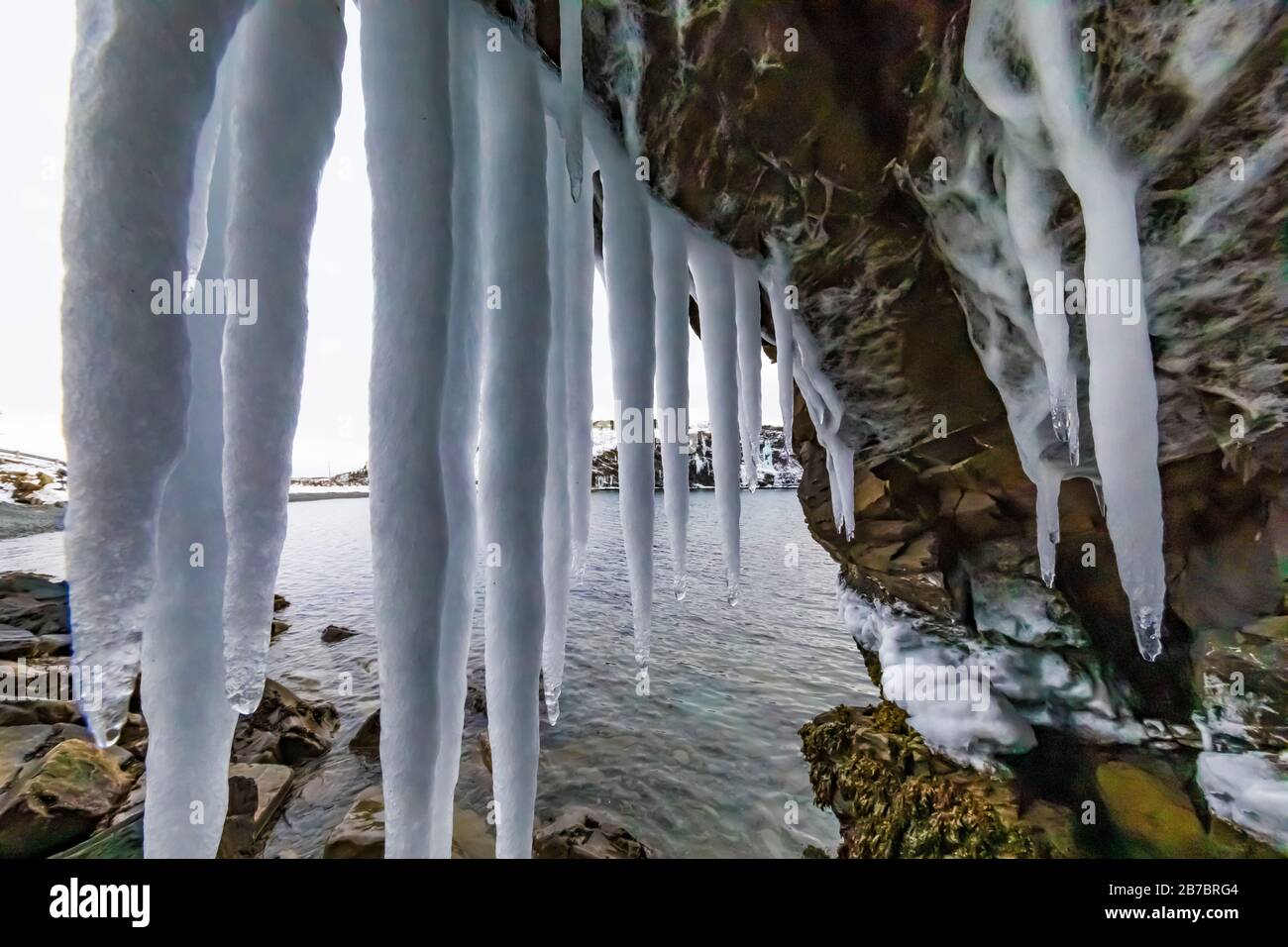 Frozen seeps forming icicles and waterfalls along the rocky cliffs of Herring Cove, near Champney's West in Newfoundland, Canada Stock Photo