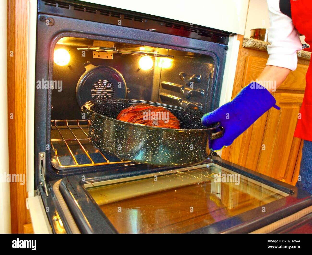 A Christmas Ham sliced up into many pieces and being placed into an oven for baking. Stock Photo