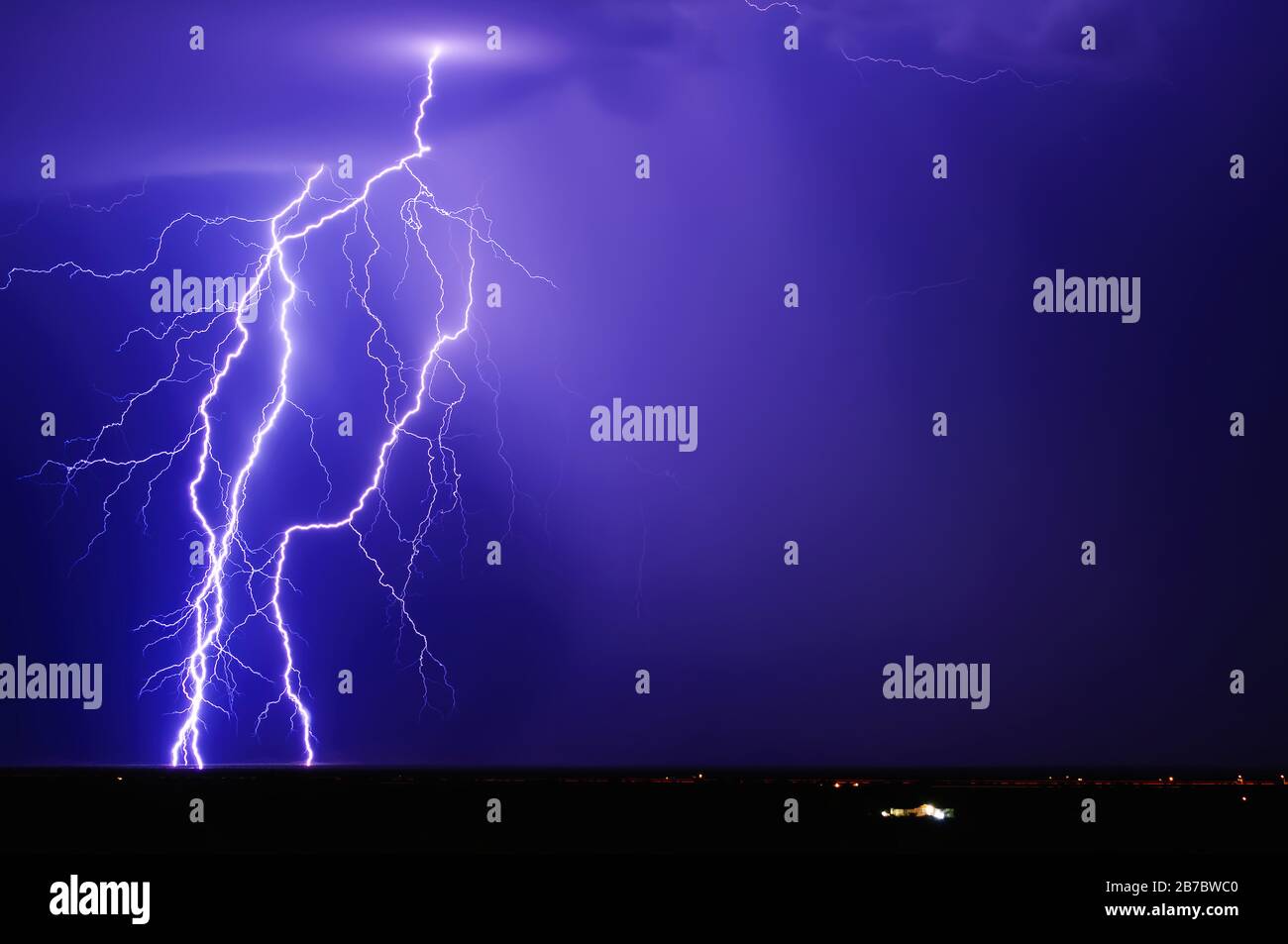 A trio of purple lightning bolts over a remote area of Arizona west of the tiny town of Tonopah during the 2013 Monsoon Season. The lone house in the Stock Photo