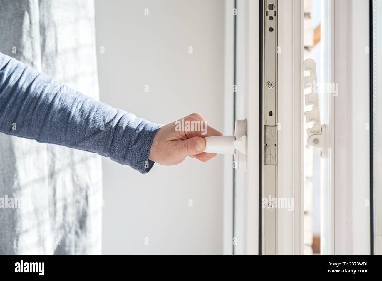 Hand opens a PVC window, holding the handle in a horizontal position ...