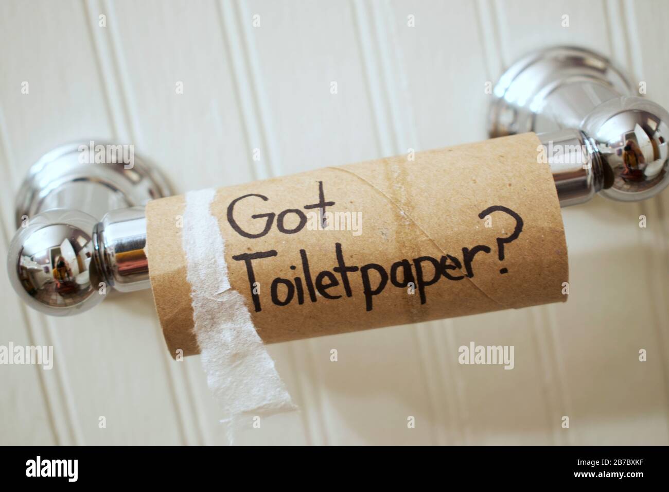 'Got Toilet Paper?' written on toilet paper roll with sharpie as it hangs on the wall on a silver spool. Stock Photo