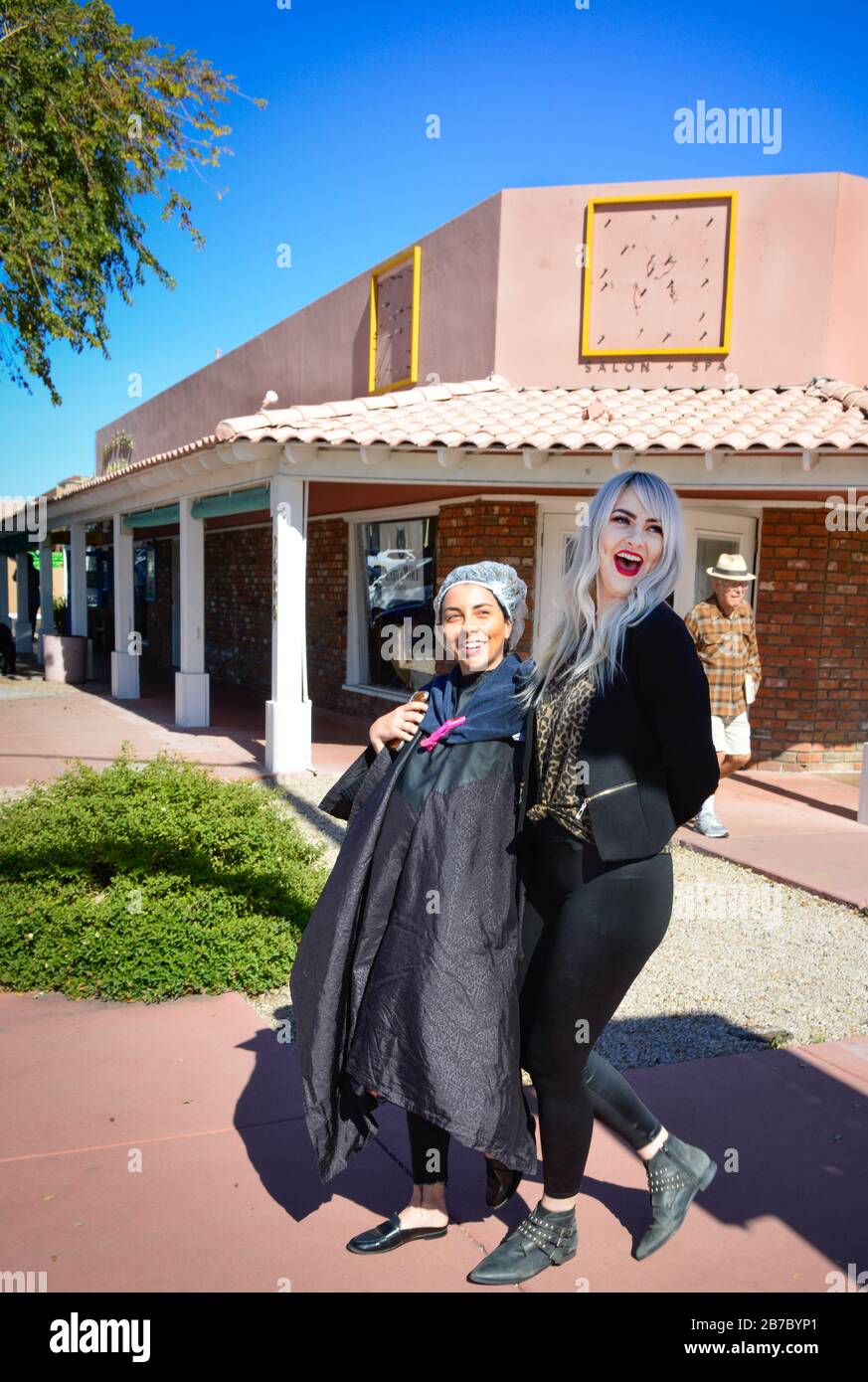 A trendy hair stylist from Lady and Wolf Hair Salon laughs & walks with her  smocked client with shower cap covered wet hair in old town Scottsdale, AZ  Stock Photo - Alamy