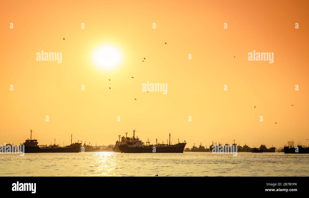 Commercial ships on anchorage in the Karnaphuli River in Bangladesh at sunset Stock Photo