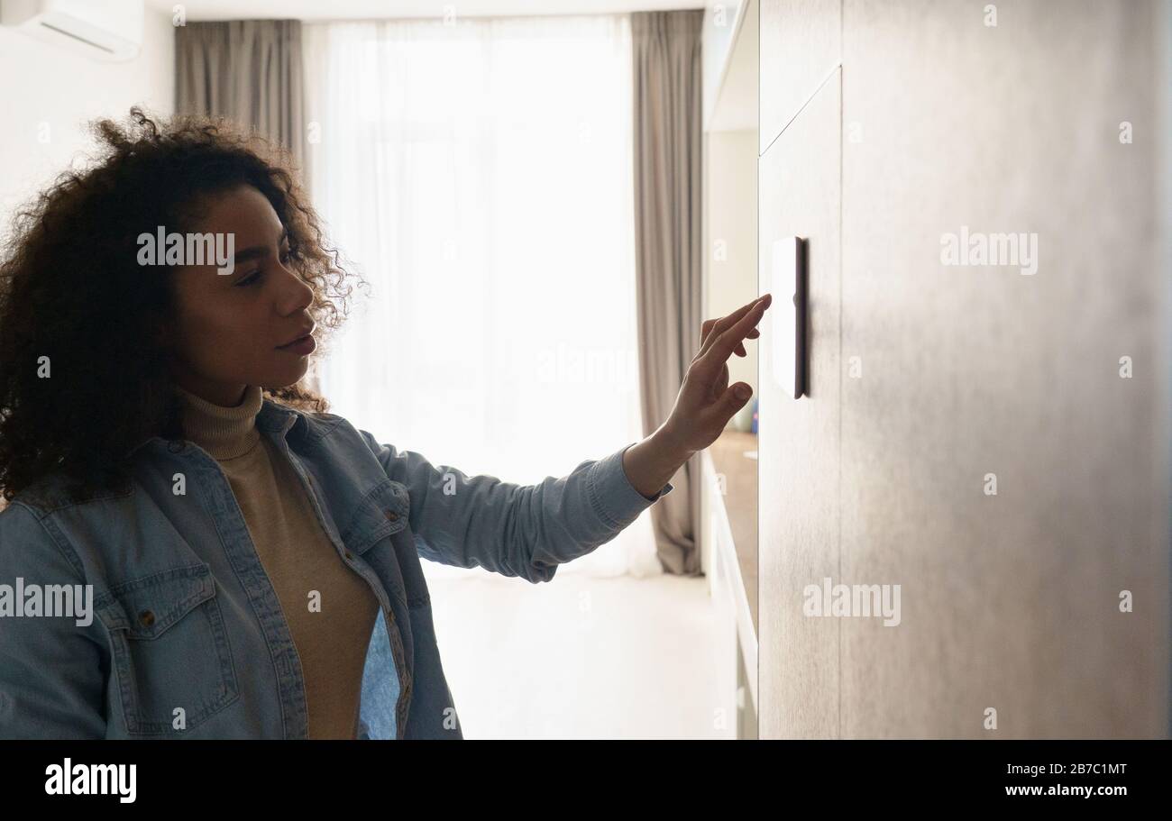 Young african girl setting remote control panel smart home concept copy space. Stock Photo