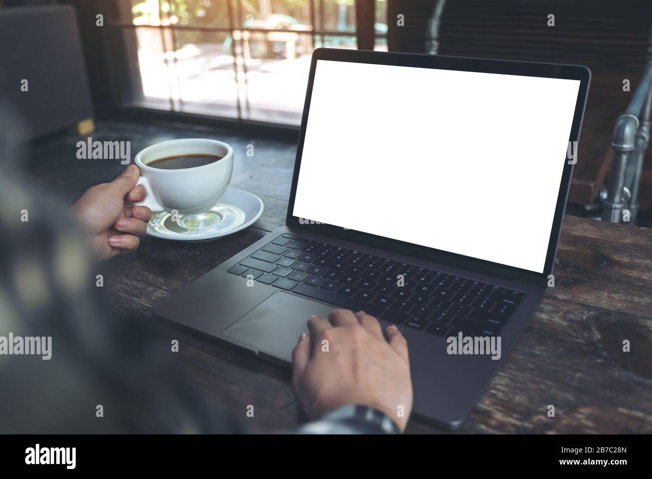 Mockup image of a woman using laptop with blank white desktop screen ...