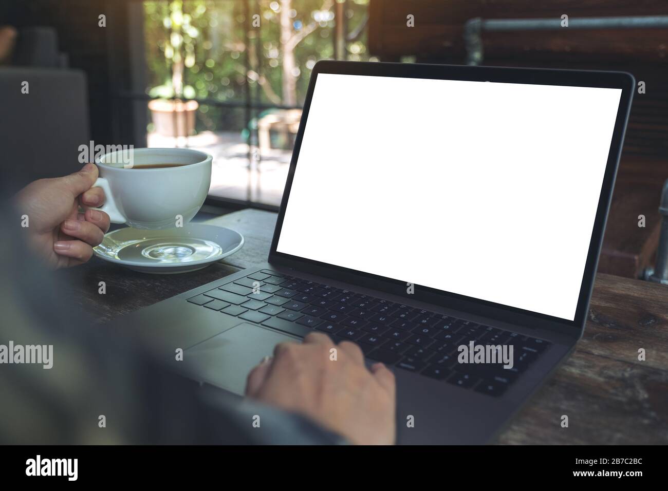 Mockup image of a woman using laptop with blank white desktop screen ...