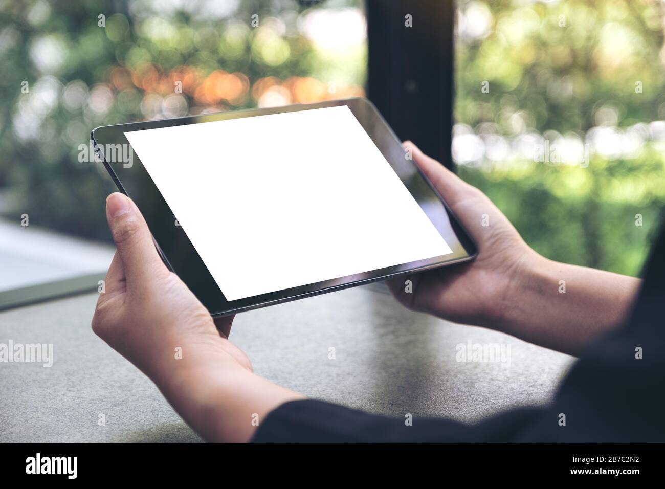 Mockup image of hands holding black tablet pc with blank white desktop ...