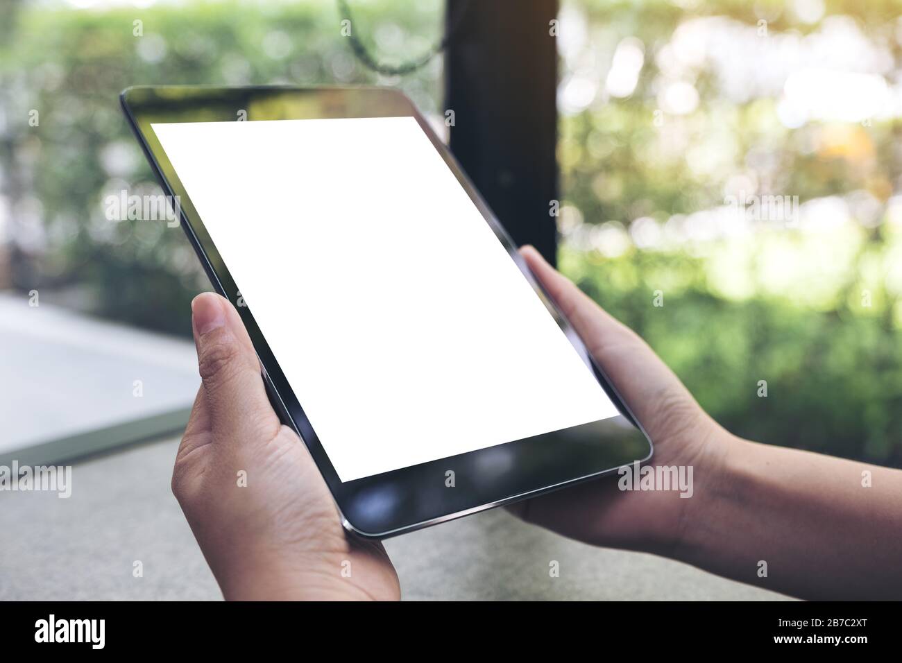 Mockup image of hands holding black tablet pc with blank white desktop ...