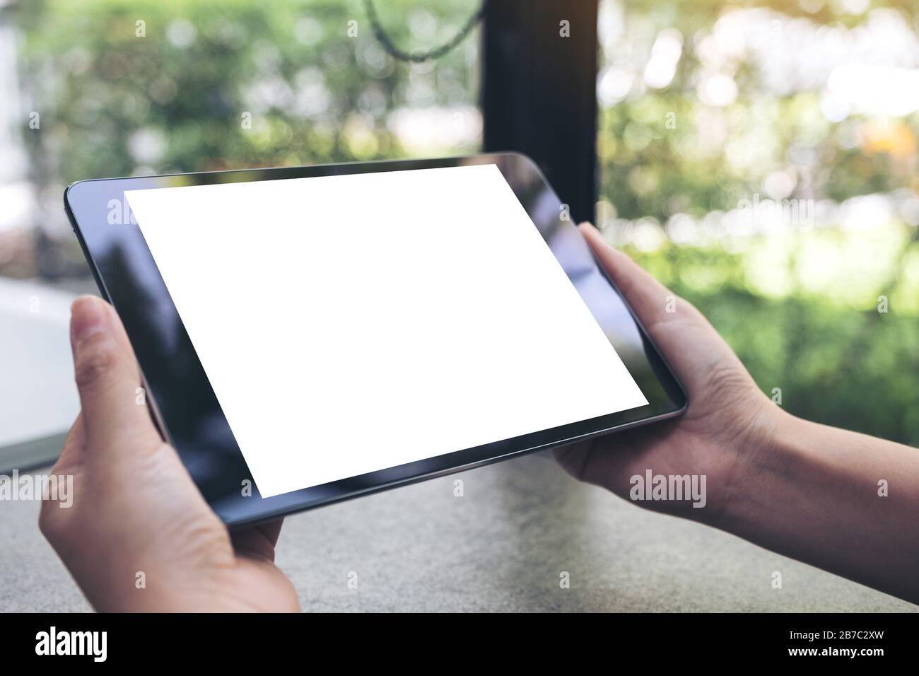 Mockup image of hands holding black tablet pc with blank white desktop ...