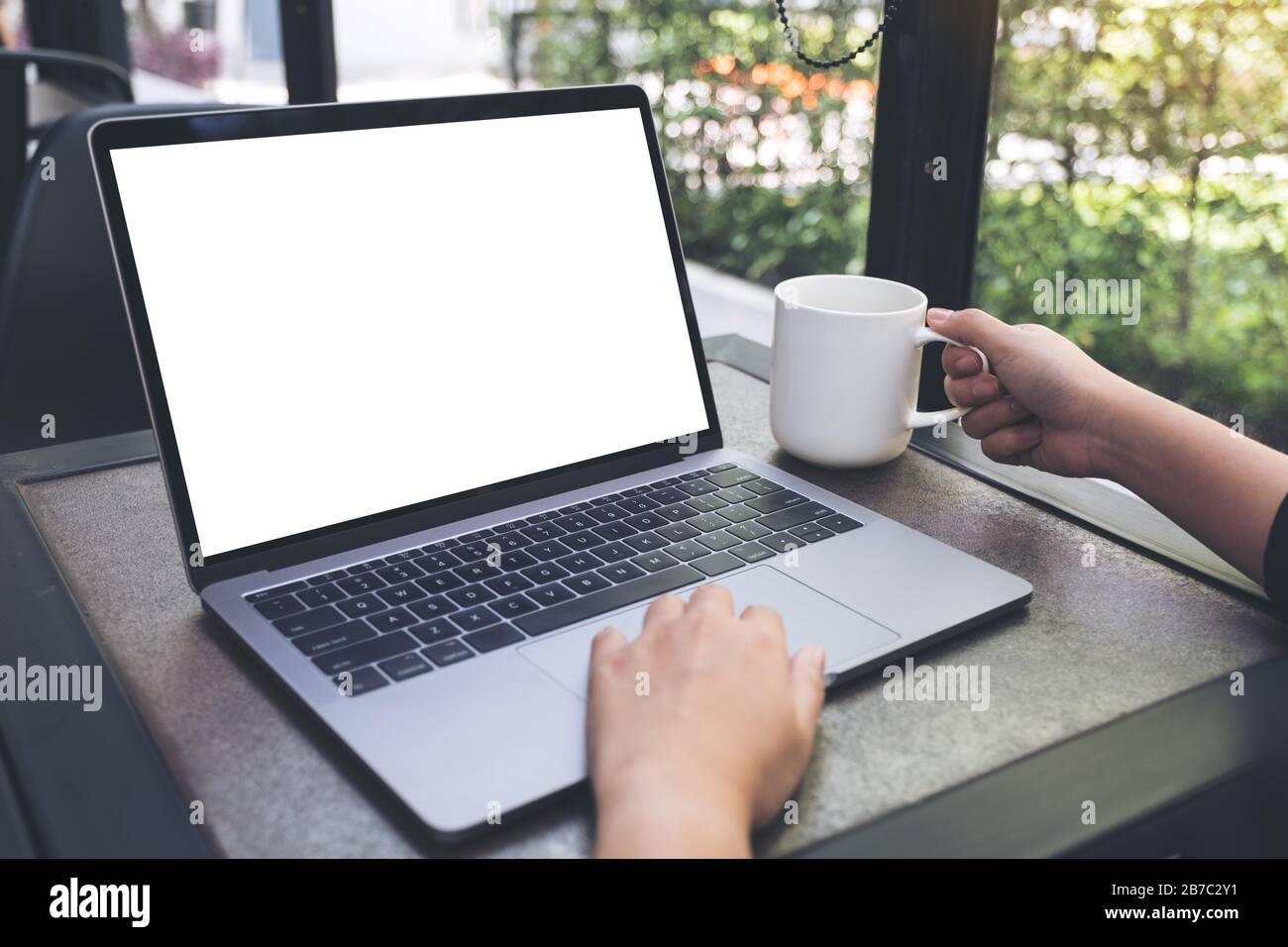 Mockup image of a woman using laptop with blank white desktop screen ...