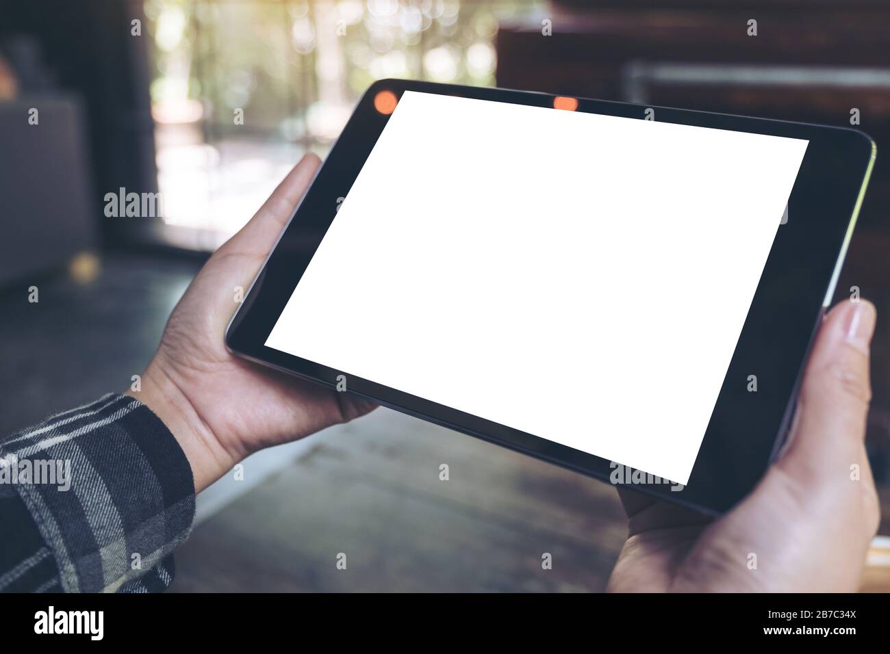 Mockup image of hands holding black tablet pc with blank white desktop ...