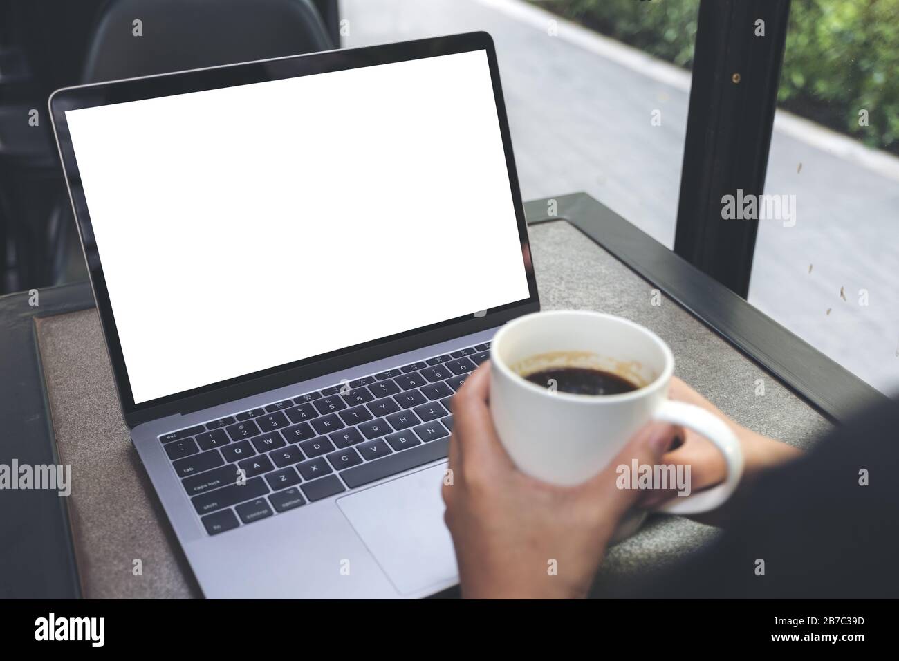 Mockup image of a woman using laptop with blank white desktop screen ...