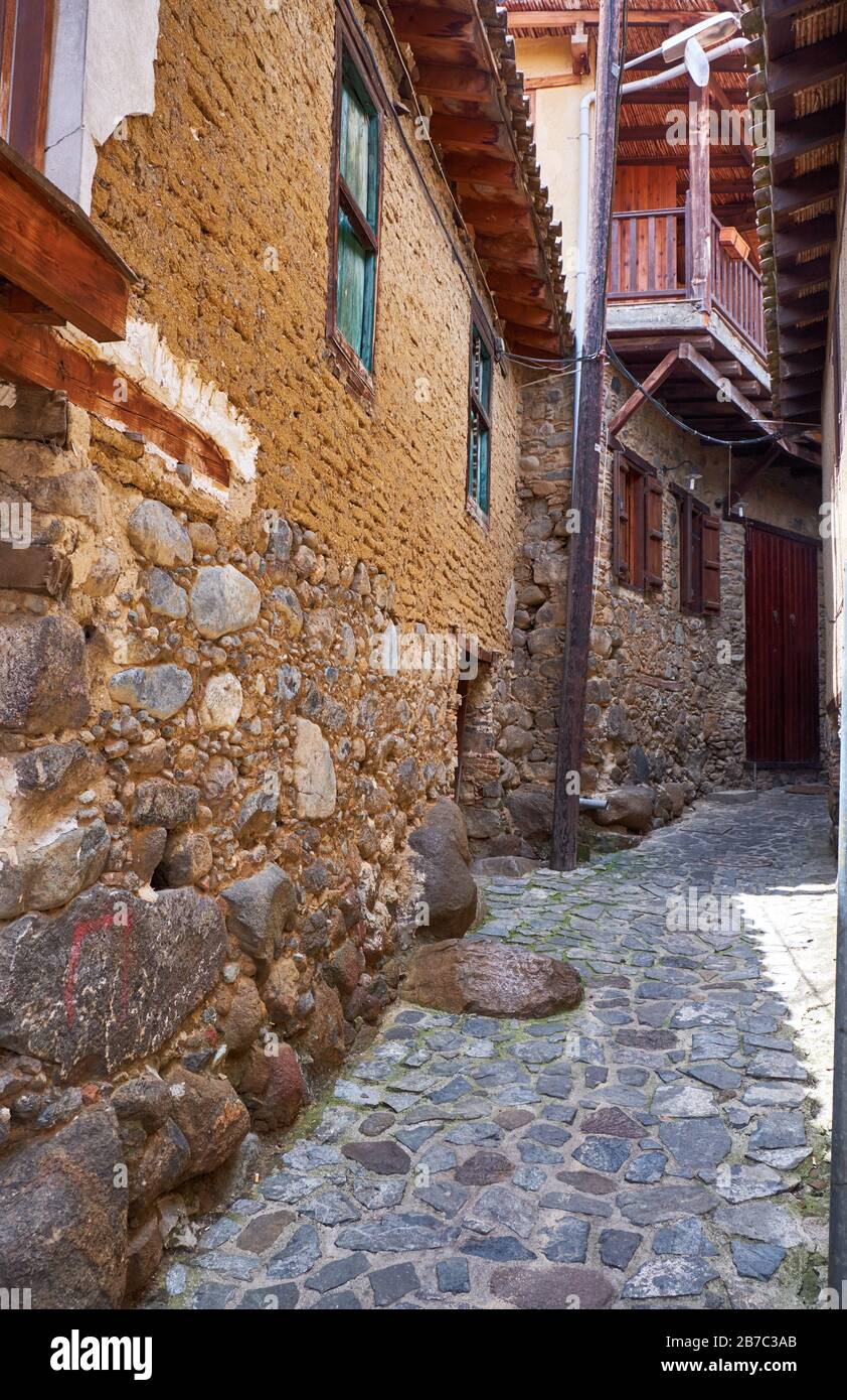 The view of the stone paved street of old Kakopetria with the traditional residential two-store house with wooden balconies and contiguous roofs. Nico Stock Photo