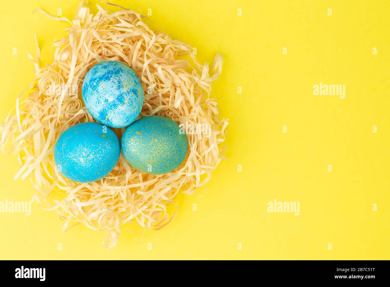 Easter egg painted blue with gold. The egg lies in a nest of wood ...