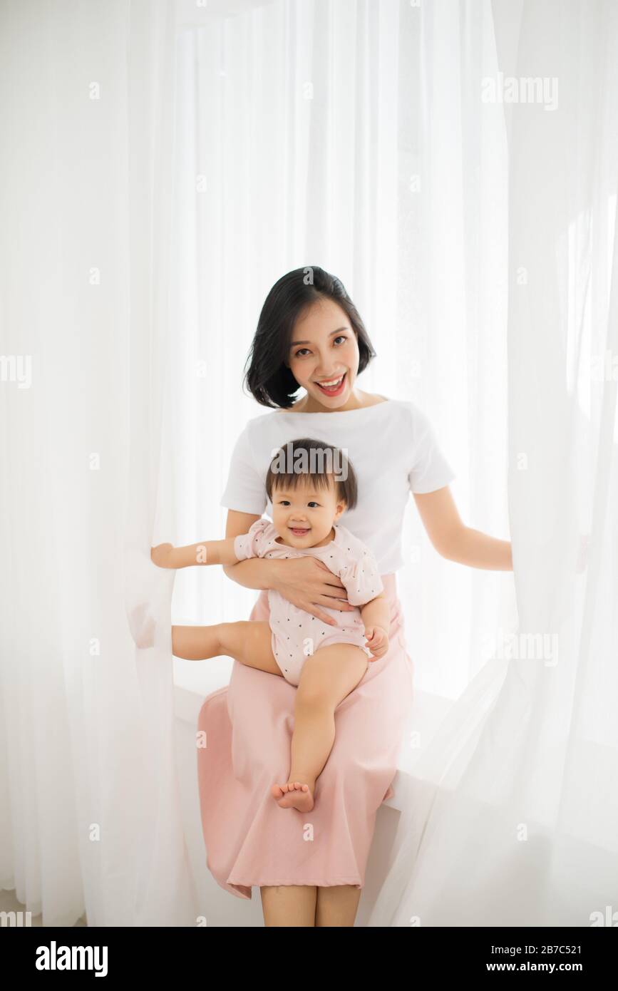 Young mother holding a baby standing in a tulle Stock Photo